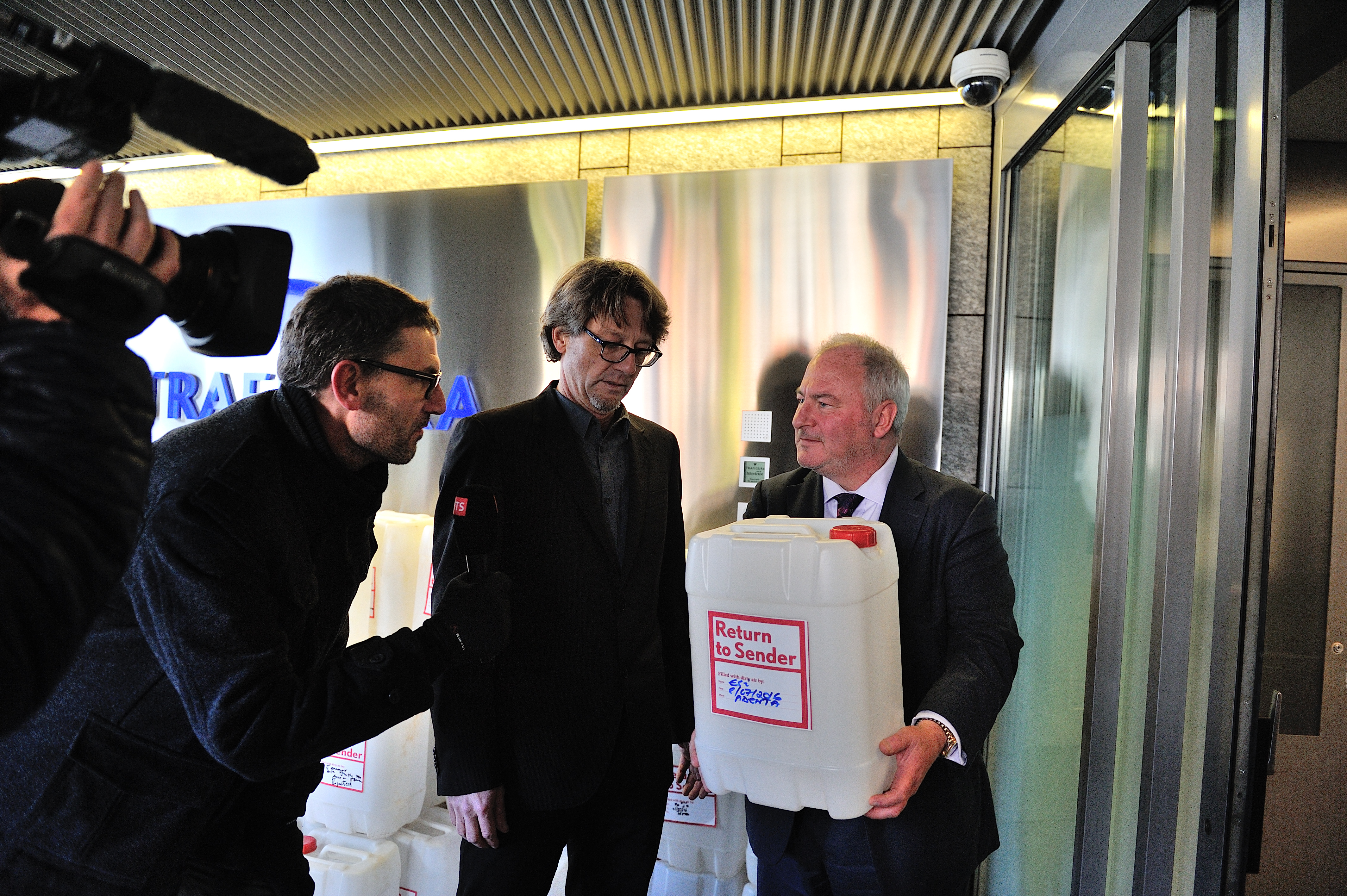 Andreas Missbach (Public Eye, à gauche) remet symboliquement un bidon d'air pollué du Ghana au porte-parole de Trafigura Andrew Gowers (à droite). Novembre 2016, Genève.